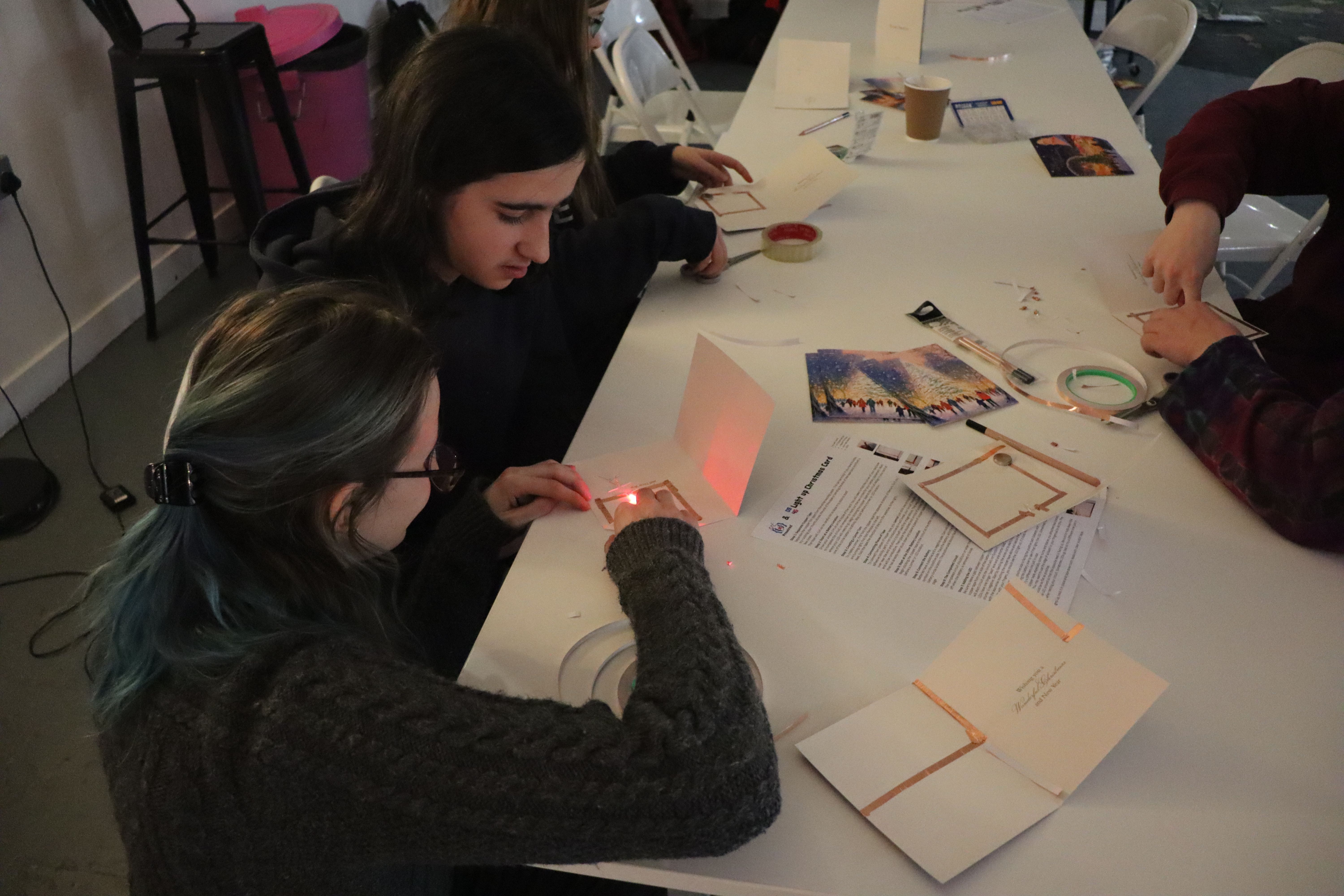 A mentor helps an attendee to create an electronic Christmas card using a micro:bit