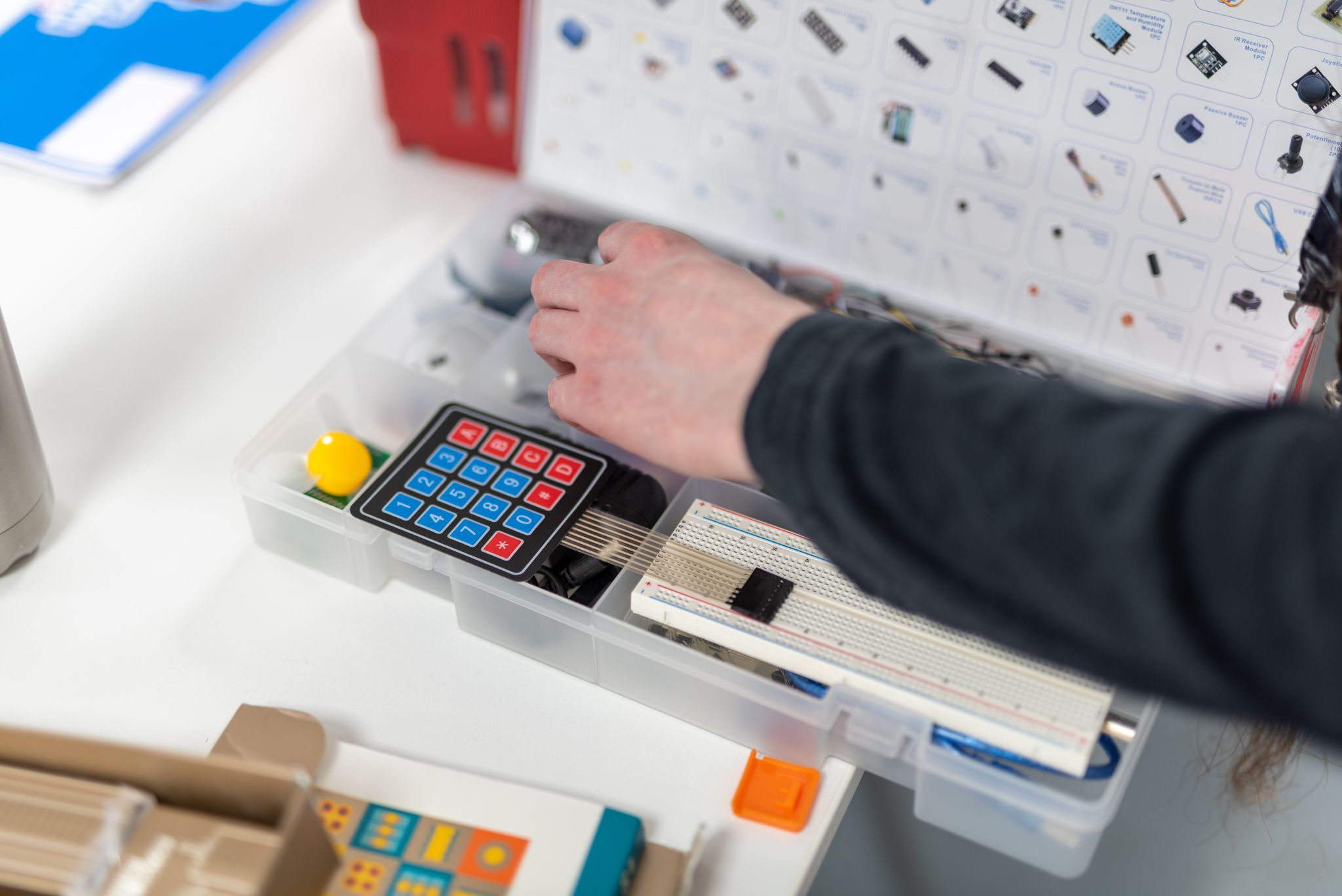 Close-up of someone taking pieces out of a box with many different electronic items