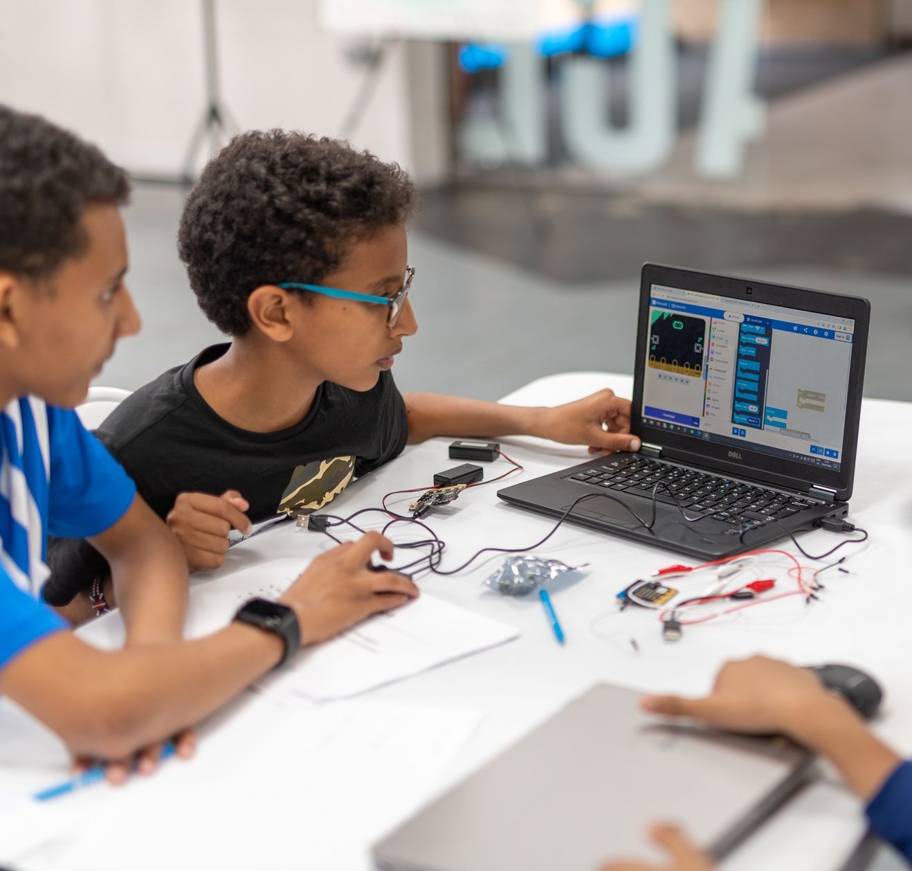 Two attendees looking at a laptop where they are coding a BBC micro:bit