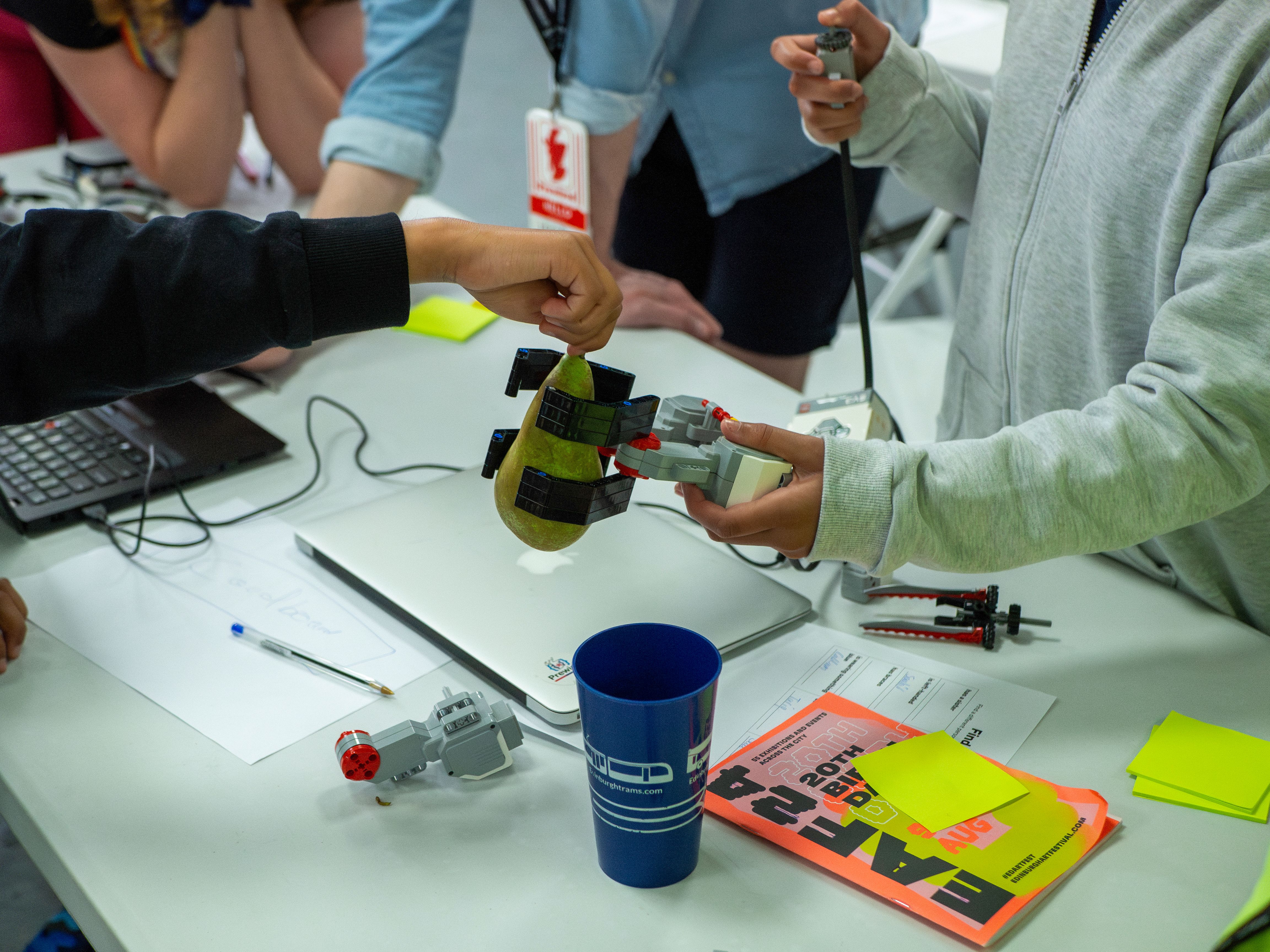 An attendee grabbing a pear using a robotic claw built from LEGO