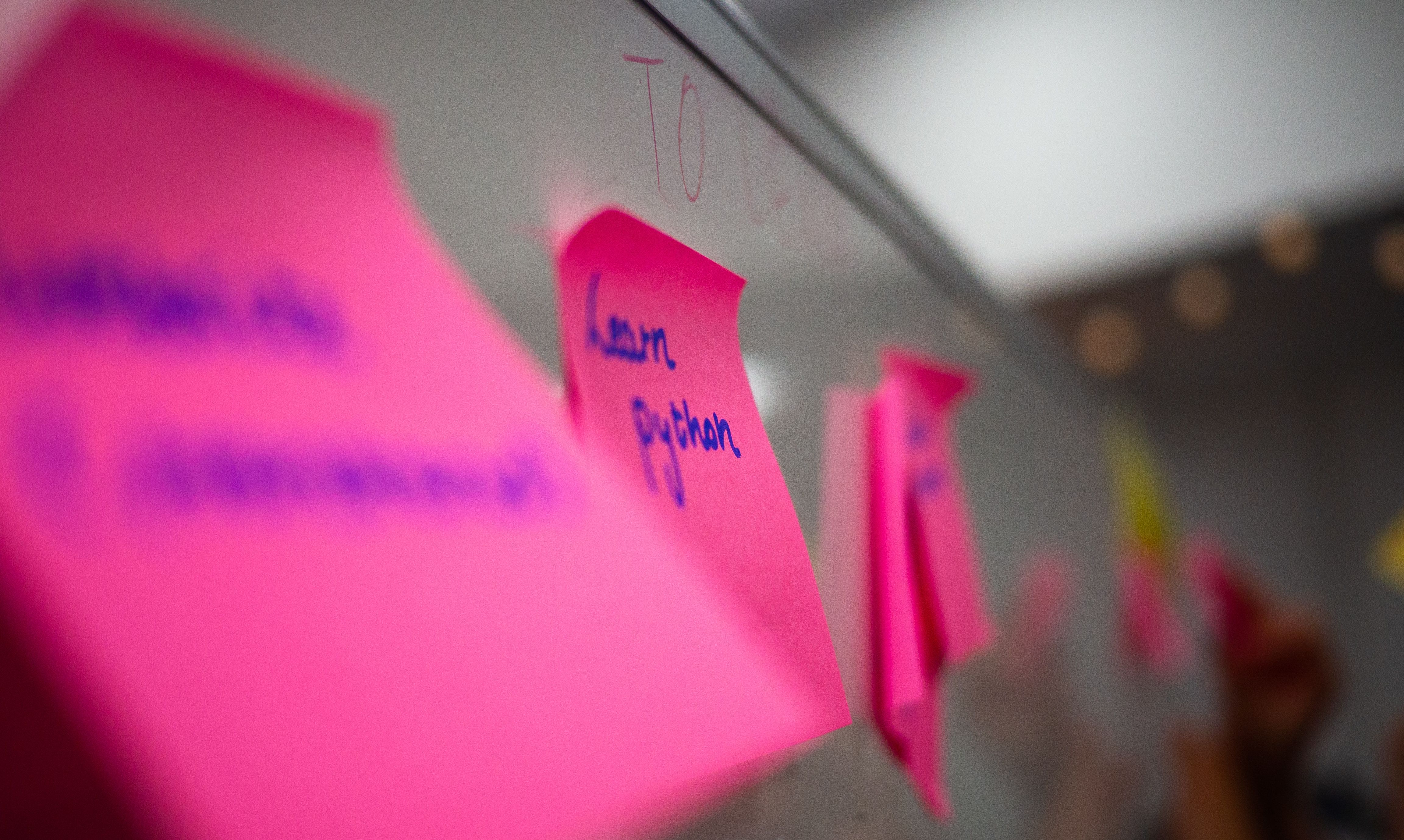 Close-up of post-its on a whiteboard, with the one in focus reading 'Learn Python'