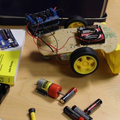 Close-up of a small robotic car wired to some batteries