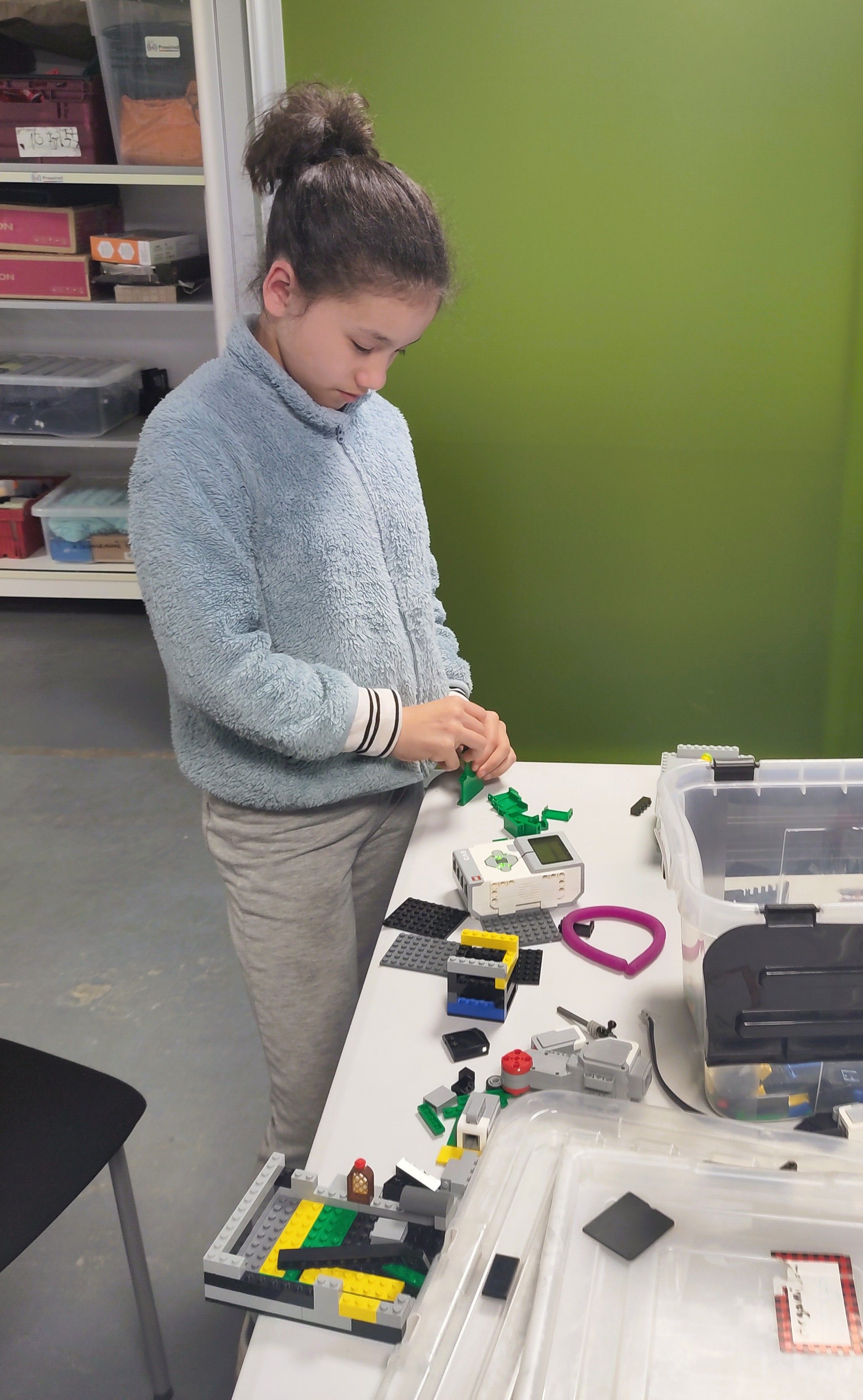 An attendee standing next to a table, building a contraption using LEGO Mindstorms pieces